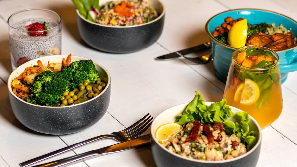 A vibrant assortment of healthy bowls and drinks showcasing fresh ingredients like broccoli and citrus.