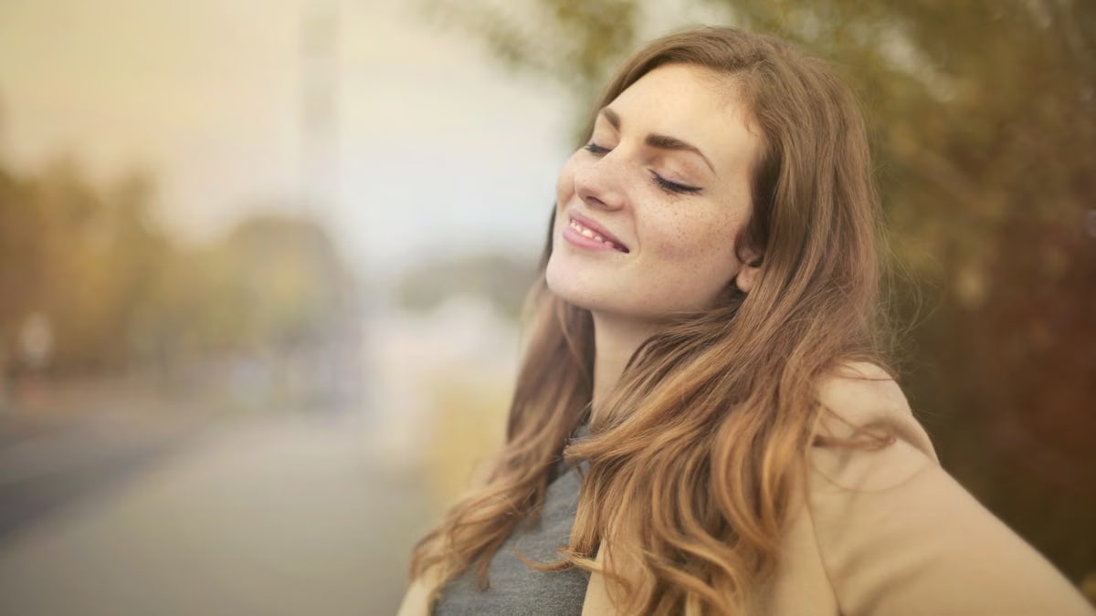 Portrait of a woman with closed eyes, enjoying the outdoors in autumn. Bright and serene.